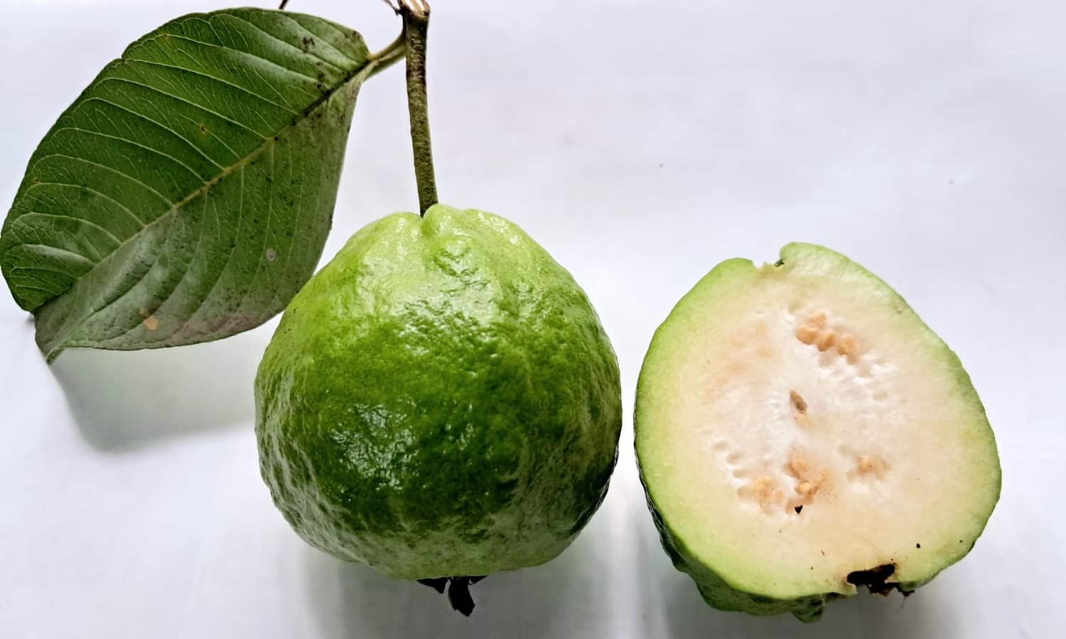 A piece of cut guava and a whole guava are kept on the table